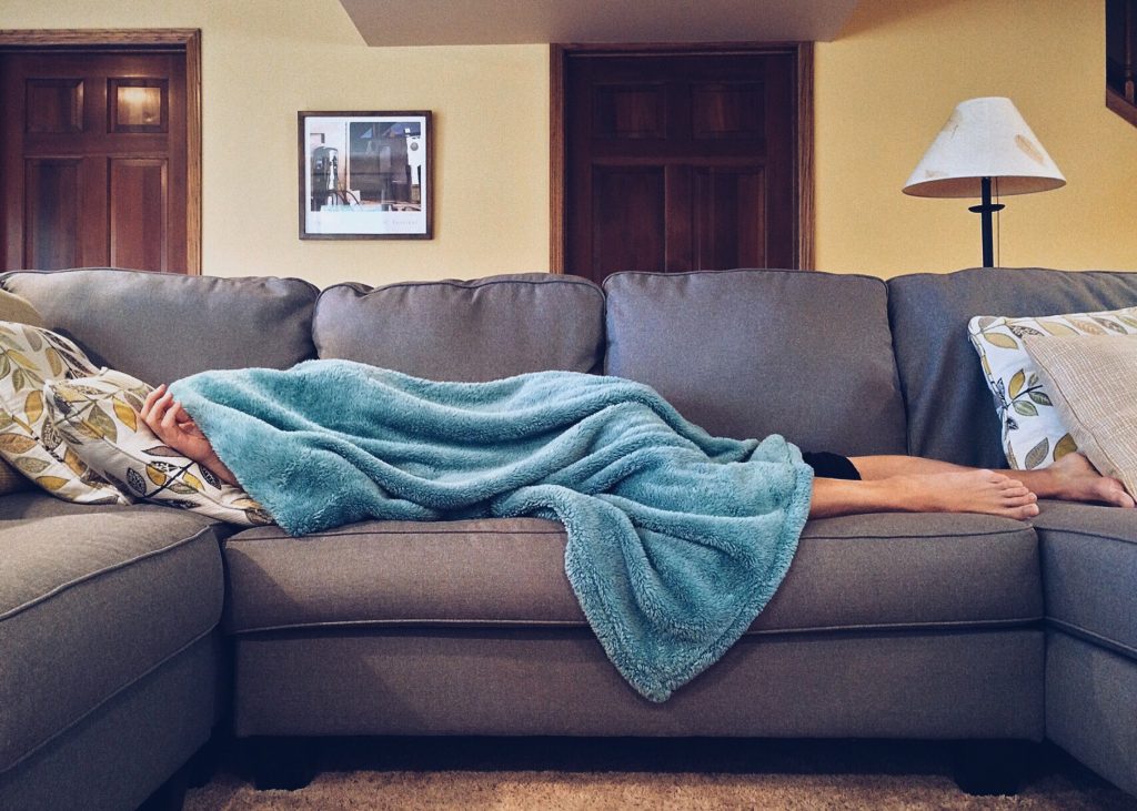 Lying down on the sofa A person lying on a sofa under a blanket